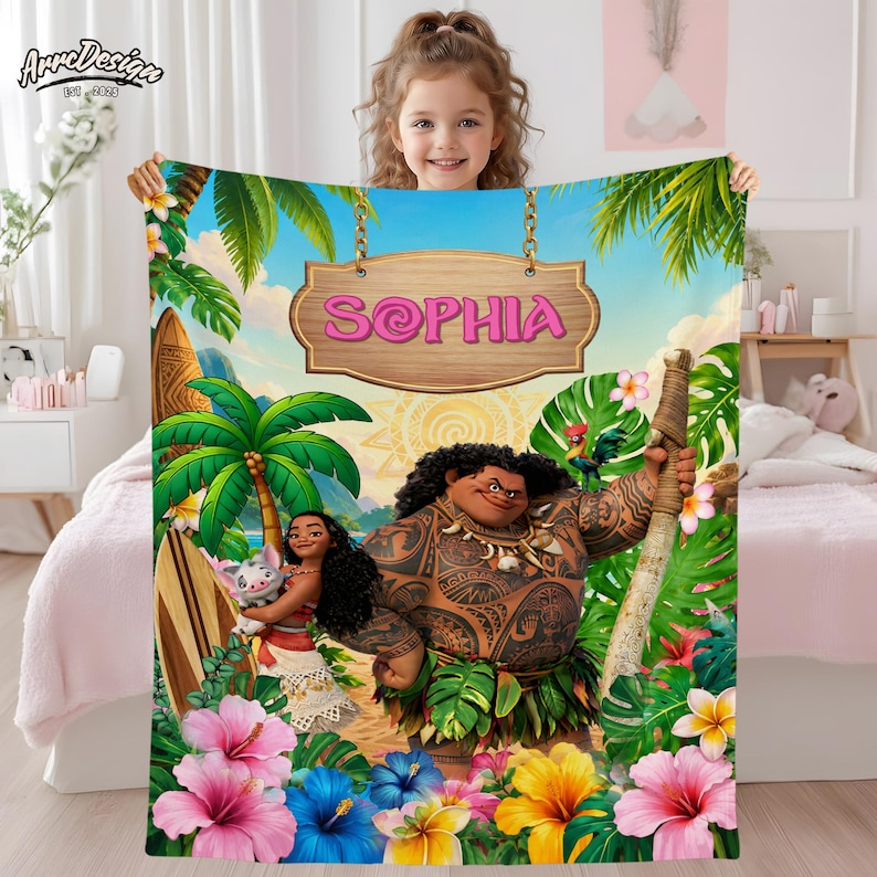 Puede incluir: Una manta personalizada con personajes de una popular pel&iacute;cula animada. La manta tiene un dise&ntilde;o vibrante con un tema tropical, que incluye palmeras, flores y el nombre "SOPHIA" en un letrero de madera. La manta es sostenida por una ni&ntilde;a.