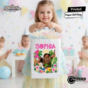 May include: A white paper gift bag with the name "SOPHIA" in pink, featuring a colorful illustration of characters and tropical flowers. The bag is held by a young girl at a birthday party.
