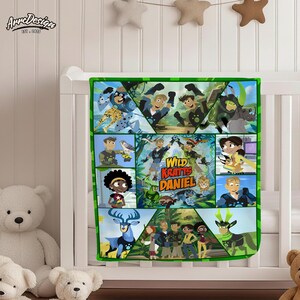 May include: A green-bordered baby blanket featuring a colorful design with characters and the text "Wild Kratts Daniel." The blanket is decorated with various animal illustrations and cartoon characters.