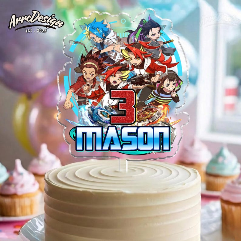 K&ouml;nnte beinhalten: Ein Kuchen mit wei&szlig;em Zuckerguss, gekr&ouml;nt von einem transparenten Acryl-Kuchenaufsatz. Der Aufsatz zeigt Zeichentrickfiguren, die Zahl 3 und den Namen "MASON" in Blau und Wei&szlig;. Cupcakes und Luftballons sind im Hintergrund.