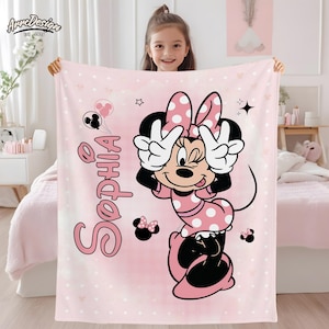 May include: Pink blanket featuring a Minnie Mouse design with polka dots and the name "Sophia" in pink script. The blanket has a light pink background with white polka dots and Minnie Mouse making a peace sign.