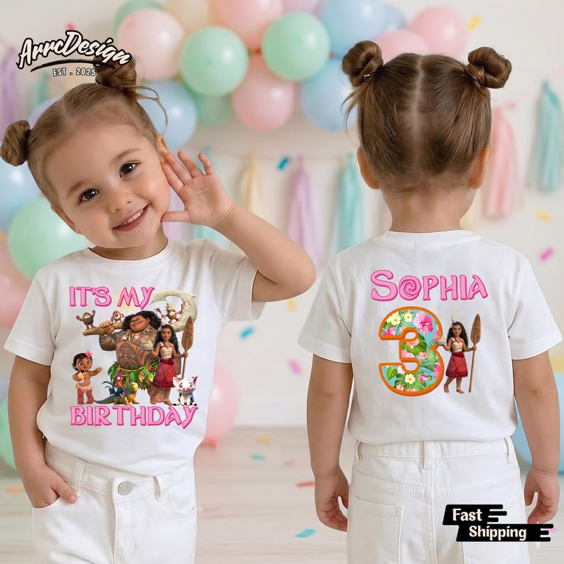 May include: White t-shirt with a colorful graphic featuring characters from the movie Moana, the text "IT'S MY BIRTHDAY" in pink, and the name "Sophia" on the back. The shirt is worn by a young child.