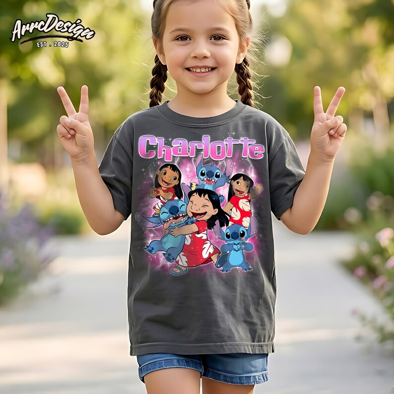May include: A charcoal grey short-sleeve t-shirt featuring a graphic print of Lilo and Stitch characters. The name Charlotte is printed in pink letters above the characters, surrounded by a pink glowing effect and sparkles on the front.