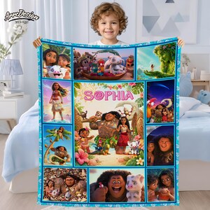 May include: A personalized fleece blanket featuring scenes from the animated movie Moana. The blanket has a blue border and includes the name "Sophia" in pink and purple. Various characters and scenes are displayed in a grid pattern.