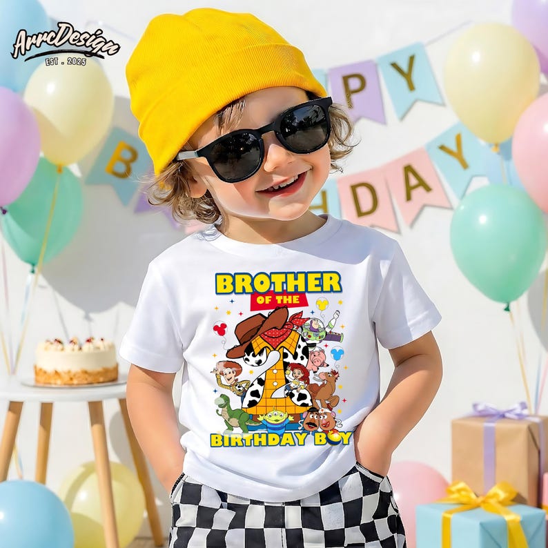 Puede incluir: Un ni&ntilde;o con una camiseta blanca con un gr&aacute;fico colorido de personajes de dibujos animados y el texto "Brother of the Birthday Boy". El ni&ntilde;o tambi&eacute;n lleva un gorro amarillo y gafas de sol. Globos y una pancarta de cumplea&ntilde;os en el fondo.