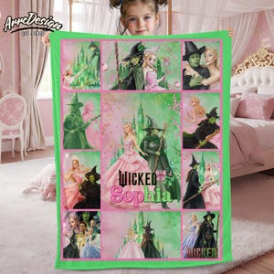 Peut inclure: Une couverture verte et rose avec des illustrations de personnages de la comédie musicale "Wicked". La couverture a une bordure verte et comprend le nom "Sophia". Les images incluent la méchante sorcière de l'Ouest et Glinda.