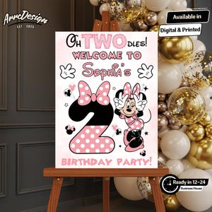 May include: A pink and white birthday party sign featuring Minnie Mouse and the text "Oh Twodles! Welcome to Sophia's Birthday Party!" The number 2 is pink with white polka dots. The sign is displayed on a wooden easel.