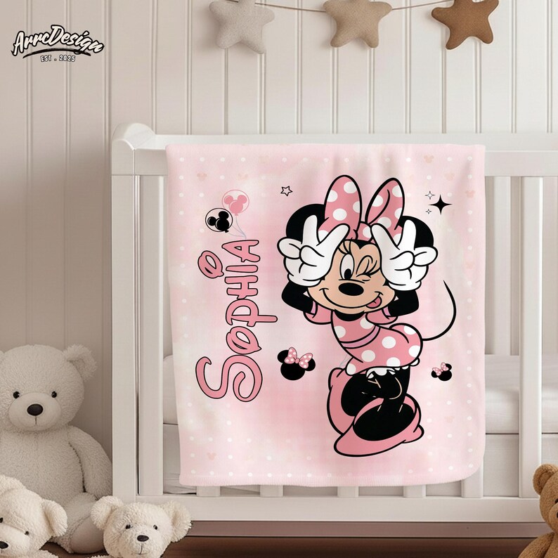 May include: A pink baby blanket with a Minnie Mouse design and the name "Sophia" in a cursive font. The blanket has a polka dot pattern and Minnie Mouse is making a peace sign with her hands.