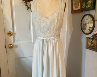 May include: A light blue, sleeveless, vintage nightgown with lace detailing and a satin ribbon at the waist.