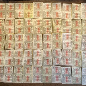 May include: A collection of vintage rectangular labels with a cream background. Each label features a red and white illustration of a structure and text. The labels are arranged closely together, covering most of the surface.