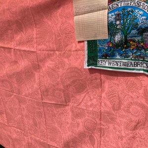 May include: Coral-colored fabric with a seashell pattern, hanging on a clothesline. A vintage receipt and a blue and green fabric with the text "WEST HAND PRINT FASHIONS" are also visible.