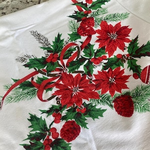 May include: White tablecloth with a festive Christmas design. Features red poinsettias, holly, pine needles, red berries, and ribbons. The design is printed on the fabric, creating a seasonal and decorative look for holiday gatherings.