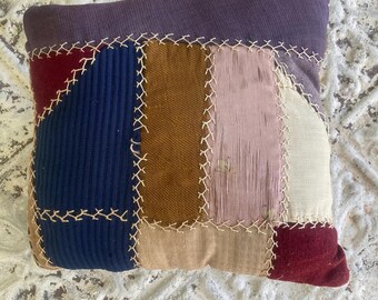 Almohada pequeña antigua de retazos con puntada de pluma y telas en tonos joya.