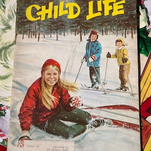 May include: A vintage Child Life magazine cover featuring a girl in a red jacket and a yellow hat sitting on a sled in a snowy forest. Two other children are skiing in the background. The magazine cover is dated 1967.