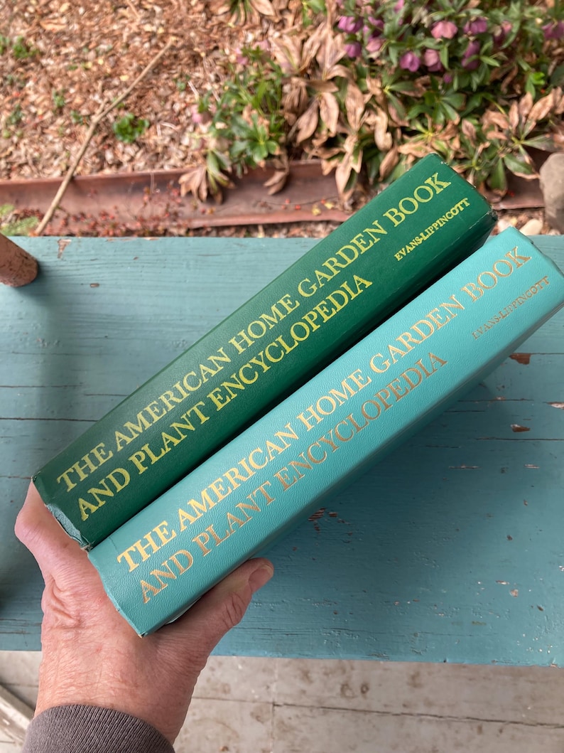 May include: Two green hardcover books titled "The American Home Garden Book and Plant Encyclopedia". The top book has the publisher "Evans-Lippincott" printed on the spine. The bottom book has the publisher "Iman's Lippincott" printed on the spine.
