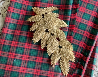 Broche vintage con rama de hoja perenne en tono dorado. Joyería llamativa.