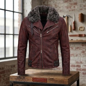 May include: A dark red leather jacket featuring a thick, grey faux fur collar, a diagonal front zip closure, multiple silver-toned zipped pockets, and adjustable buckle straps at the waist and collar for a secure, structured fit.