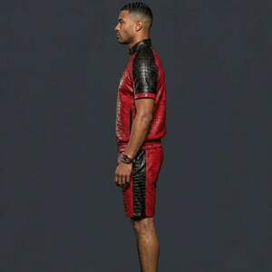 May include: A two-piece set consisting of a short-sleeved shirt and shorts, both featuring a red and black textured crocodile-skin pattern. The shirt has a high collar and black sleeves, while the shorts include a vertical black side stripe.