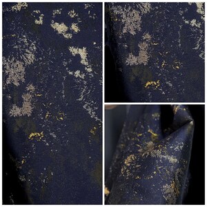 May include: A dark navy blue fabric with a distressed metallic gold and silver leaf pattern. The fabric has a textured appearance, with the gold and silver accents scattered across the surface. The overall effect is a blend of elegance and grunge.