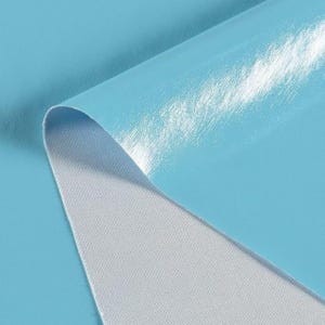 May include: A close-up of a piece of light blue fabric with a glossy, reflective surface. The fabric is folded over, revealing a white, textured underside. The material appears to be a synthetic textile, possibly vinyl or a similar material.