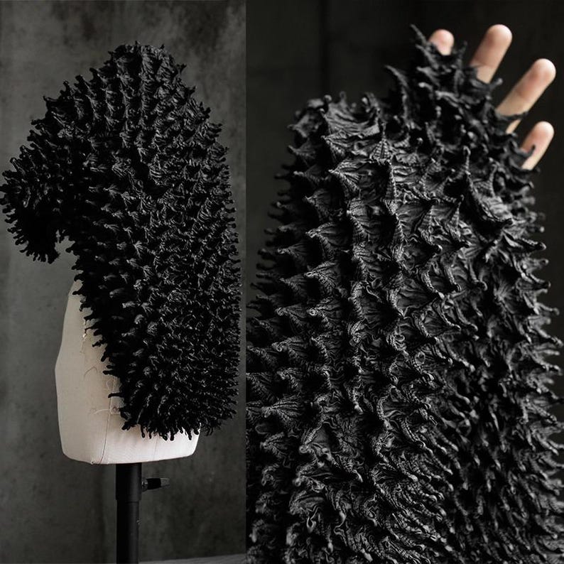 May include: A black, textured garment with a unique, spiky design. The garment is displayed on a mannequin and also shown in a close-up view, highlighting the intricate details of the fabric. The overall aesthetic is avant-garde and artistic.