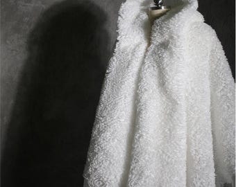 May include: A white, textured coat with a large, hooded collar. The coat is displayed on a mannequin against a dark gray background. The fabric has a soft, plush appearance.