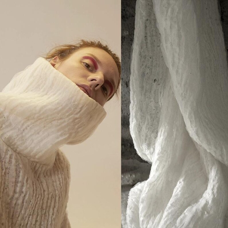 Op de afbeelding: Een persoon draagt een getextureerde, gebroken witte coltrui met een hoge, brede kraag. De persoon heeft rode oogmake-up. Rechts een close-up van een witte, getextureerde stof.