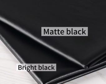 Puede incluir: Primer plano de dos muestras de tela negra. Una está etiquetada como "Matte black" y la otra como "Bright black". Las telas están dobladas, mostrando las diferencias de textura y brillo entre los dos materiales. La imagen resalta el contraste en los acabados.