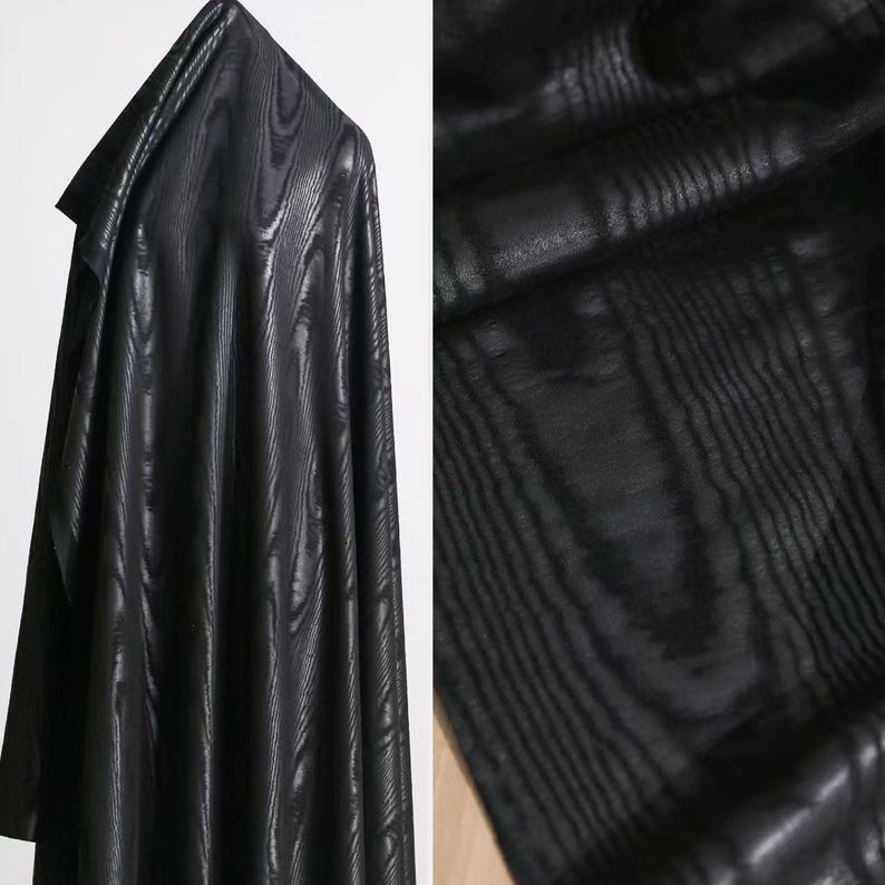 Puede incluir: Una pieza de tela negra con un patr&oacute;n sutil y repetitivo de veta de madera. El material est&aacute; drapeado para mostrar su textura y brillo, con la superficie oscura que muestra l&iacute;neas verticales que imitan la apariencia natural de la madera.