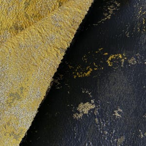 May include: Close-up of two fabric swatches. One is a textured gold fabric with a subtle pattern. The other is a black fabric with gold flecks, creating a contrasting visual. The fabrics are angled against each other.