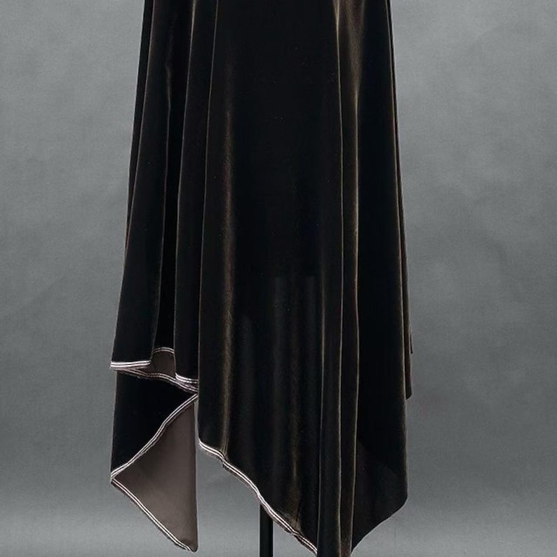 May include: A dark brown velvet fabric draped over a stand. The fabric has a soft, lustrous appearance with a contrasting light-colored trim along the edges. The background is a solid gray.
