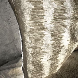 May include: Close-up of a textured fabric with a repeating pattern of vertical, stitched lines. The fabric has a neutral color palette, with shades of beige and off-white. The texture appears soft and slightly wrinkled, suggesting a linen or similar material.