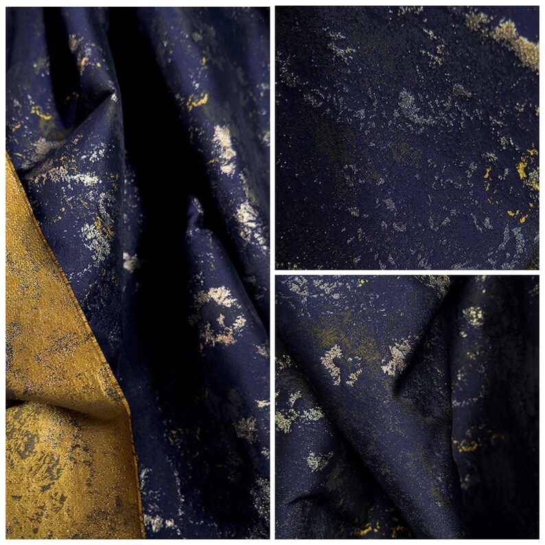 May include: Close-up of a textured fabric with a dark navy blue base and gold and silver metallic accents. The fabric is folded, revealing the texture and sheen of the material. The overall effect is a luxurious, abstract design.