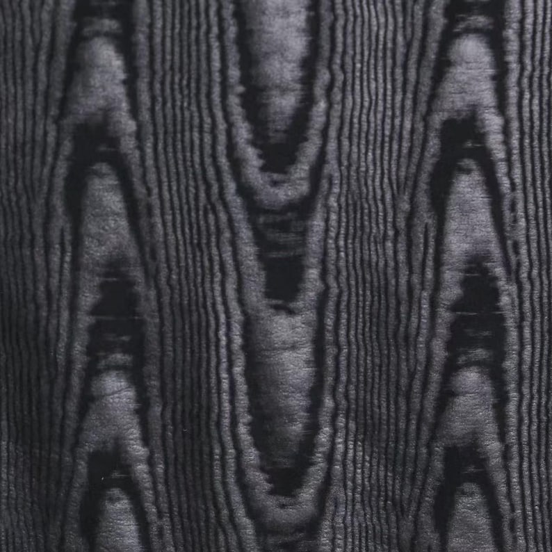 Puede incluir: Primer plano de un patr&oacute;n de vetas de madera gris oscuro. La veta de la madera tiene una orientaci&oacute;n vertical con formas org&aacute;nicas onduladas y l&iacute;neas finas y paralelas. El efecto general es una apariencia texturizada y natural.