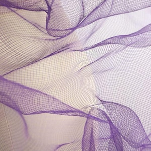 May include: Close-up of a sheer, purple fabric with a grid-like pattern. The fabric is draped and folded, creating shadows and highlights. The material appears lightweight and airy, with a subtle sheen.