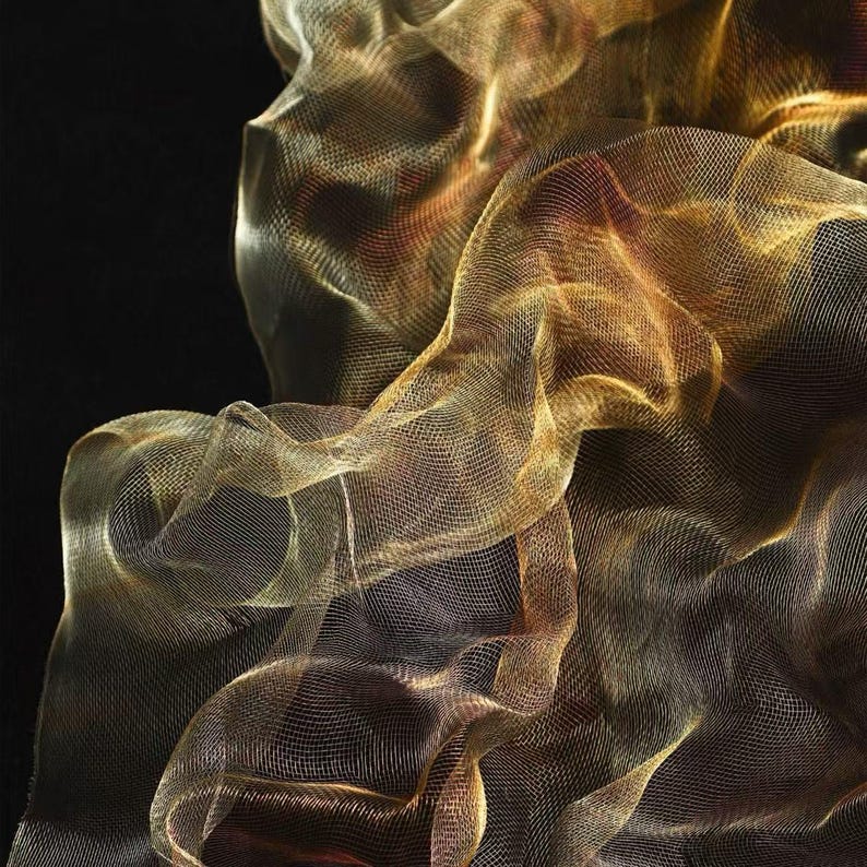 May include: Abstract image of flowing, golden mesh fabric against a black background. The fabric appears to be layered, creating depth and texture. The lighting highlights the delicate weave and creates a shimmering effect.