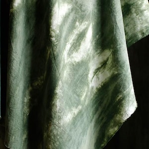 Puede incluir: Primer plano de una tela te&ntilde;ida con tinte verde y blanco. La tela tiene un aspecto fluido y texturizado con una mezcla de tonos verdes claros y oscuros. El dise&ntilde;o crea un efecto veteado, con vetas blancas.