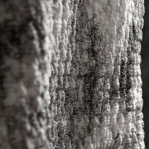 Puede incluir: Primer plano de una superficie texturizada y monocromática. La superficie parece estar compuesta por formas irregulares en capas, con una mezcla de tonos blancos y grises oscuros. La textura es áspera y desigual, creando una sensación de profundidad e interés visual.