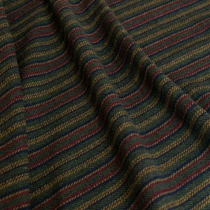 May include: Close-up of a textured fabric with diagonal stripes. The fabric features a pattern of alternating stripes in dark green, navy blue, red, and gold. The fabric is draped, showing the texture and folds of the material.