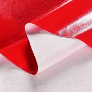 Pode incluir: Uma imagem em close-up de um tecido vermelho brilhante com uma parte traseira branca. O material vermelho está dobrado, revelando o tecido branco por baixo. A superfície brilhante reflete a luz, criando destaques e sombras.