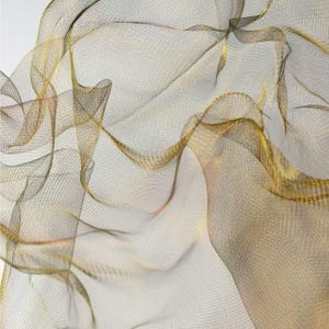 May include: Abstract image of flowing fabric with a net-like texture. The fabric has a gradient of colors, including gold, brown, and beige. The material appears to be lightweight and airy, with a delicate, woven pattern.