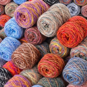 May include: A collection of colorful yarn skeins in various shades of blue, brown, orange, purple, and yellow. The yarn is tightly wound, showing the texture and color variations within each ball. Ideal for knitting and crochet projects.