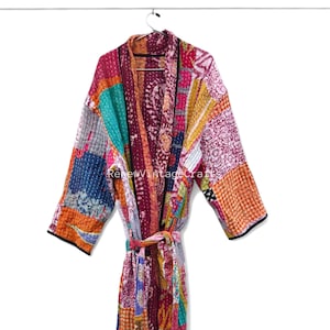 May include: A colorful patchwork robe with a tie belt, hanging on a metal hanger. The robe features a variety of patterns and colors, including pink, orange, teal, and purple. The sleeves have black trim. The text "RenewVintageCrafts" is visible.