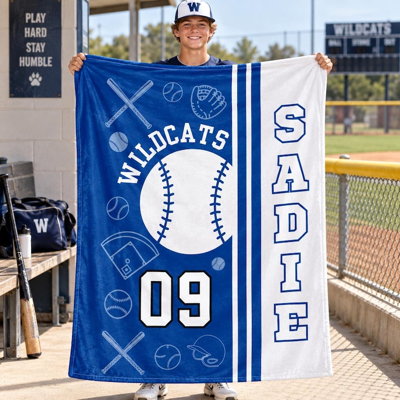 May include: A blue and white fleece blanket featuring a large baseball graphic, the text WILDCATS, the number 09, and the name SADIE in vertical block letters. The design includes baseball bats, gloves, and balls on a blue background.