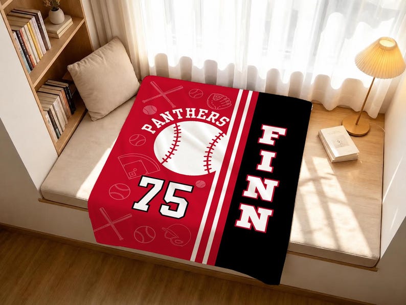 May include: A rectangular blanket featuring a red section with a white baseball graphic, the text PANTHERS, the number 75, and various baseball icons. A black vertical stripe on the right side displays the name FINN in large white capital letters.