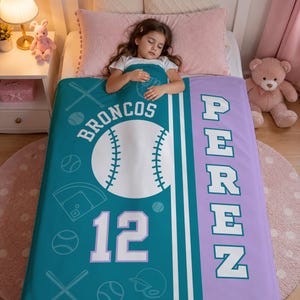 May include: A teal and lavender personalized blanket featuring a large white baseball graphic, the text BRONCOS, the number 12, and the name PEREZ in block letters. The design includes white line art of baseball bats, balls, and a catcher's mask.