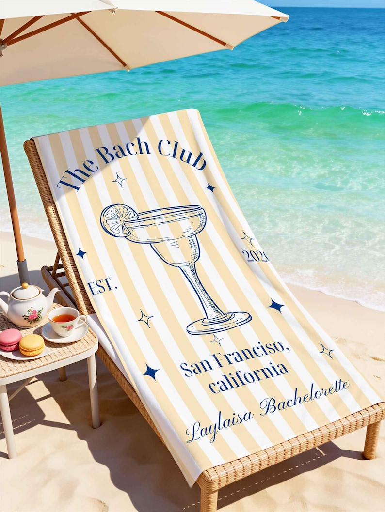 May include: Beach scene with a striped beach towel on a wicker lounge chair. The towel has a margarita glass graphic and text that reads "The Bach Club, San Francisco, California, Laylaisa Bachelorette."