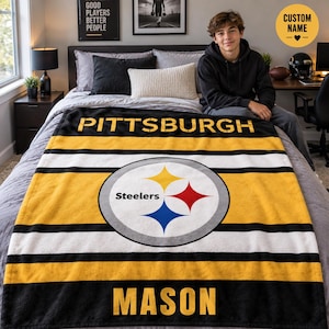 May include: A soft fleece blanket featuring the Pittsburgh Steelers logo in the center, with horizontal black, white, and yellow stripes. The text PITTSBURGH is printed at the top and the name MASON is printed at the bottom in bold yellow letters.