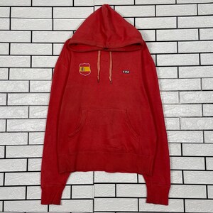 May include: A red hooded sweatshirt with a front pocket and drawstrings. The sweatshirt features a small Spanish flag patch and the word "FIFA" printed on the chest. The garment is made of a soft material and has a relaxed fit.