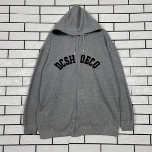 May include: A gray zip-up hoodie with a hood and the text "DCSH DECO" in black across the chest. The hoodie is made of a soft material and has a full-length zipper.